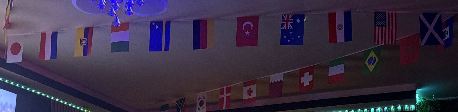 Fahnen vieler Länder unter der Decke der Koala Bar, darunter eine türkise Lichtleiste